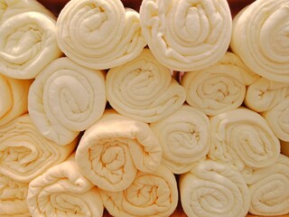 Beige towels  Several parcels are rolled up on a shelf.