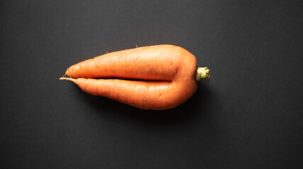 Ugly food. A large, ugly, fresh carrot on a black background. 