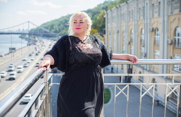 Plus size woman, American or European appearance walks in the city enjoying life. A young lady with excess weight, stylishly dressed in the center of the city. Natural beauty