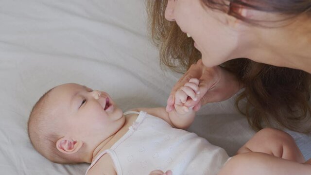 Close up mother kissing happy baby laughing enjoying loving mom nurturing toddler at home.
