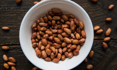 Peanut nuts in a small plate on a vintage wooden table. Peanuts nut is a healthy vegetarian protein nutritious food.