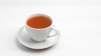 White cup of tea on a white wooden table. Copyspace.