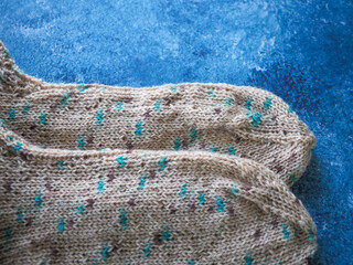 Hand knitted socks close up on blue background.