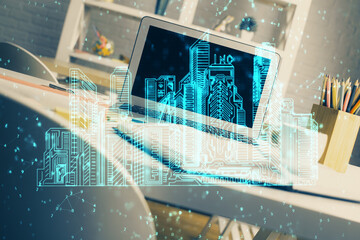 Desktop computer background in office and big town buildings hologram drawing. Double exposure. Smart city concept.