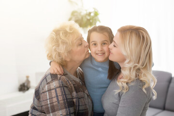 Portrait of three generations of women look at camera posing for family picture, cute little girl hug mom and granny enjoy time at home, smiling mother, daughter and grandmother spend weekend together