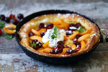 Delicious Dutch baby pancake with fruit and ice cream. Homemade fruit pie.