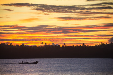 Dark silhouettes of palm trees, boat and amazing cloudy sky on sunset at tropical island in Indian Ocean. High quality photo