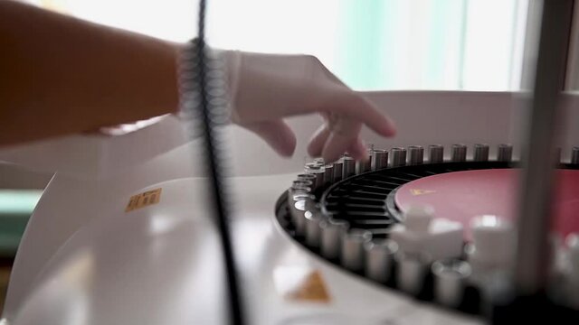 A nurse sorts blood tests in a centrifuge for examination