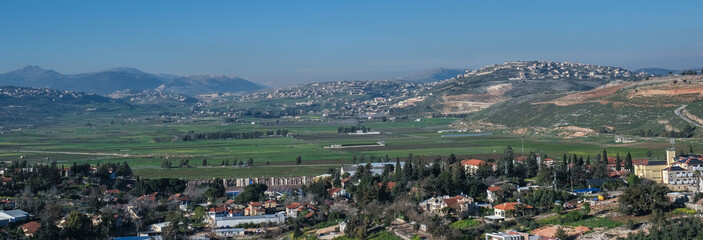 Fototapeta na wymiar View of the town of Metula, situated on the Israeli-Lebanese border, at the foot of Mount Hermon (in the background), as seen from Dado lookout point, Upper Galilee, Israel.