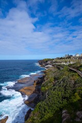 Rock cliffs over the ocean at Bronte Beach with views of the houses at Bondi Beach Sydney NSW Australia