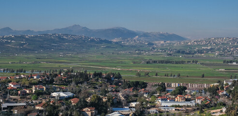 Fototapeta na wymiar View of the town of Metula, situated on the Israeli-Lebanese border, at the foot of Mount Hermon (in the background), as seen from Dado lookout point, Upper Galilee, Israel.