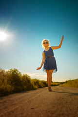 Fototapeta premium Woman walking along on a road in her blue dress