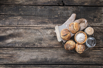 Freshly baked sourdough bread buns, water, flour and starter yeast placed on a round cooling rake