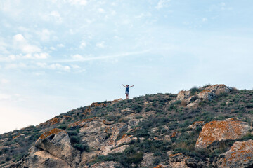 Fototapeta premium Young beautiful woman enjoying the panoramic top view of the sandy beach from the cliff.