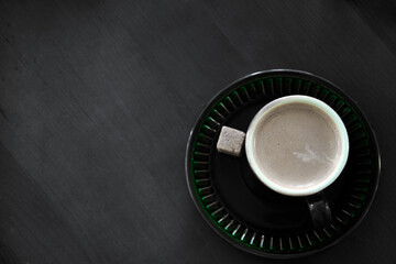 coffee Cup with a piece of cane sugar on a dark wooden background