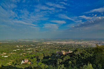 Fototapeta na wymiar Vista de sierra y ciudad de Córdoba con vegetación diversa con extensiones de estepa y nubes en el cielo