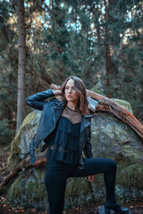 young beautiful woman in leather jacket with axe in a forest