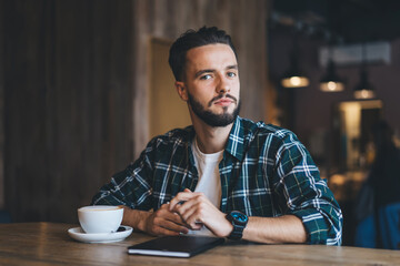 Serious man with notebook and cup of cappuccino in cafe
