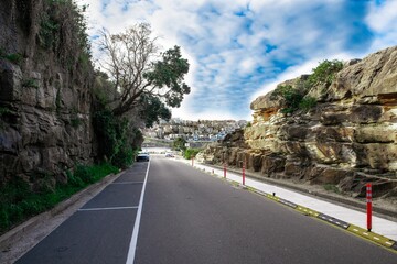 Rock cliffs over the ocean at Bronte Beach with views of the houses at Bondi Beach Sydney NSW Australia