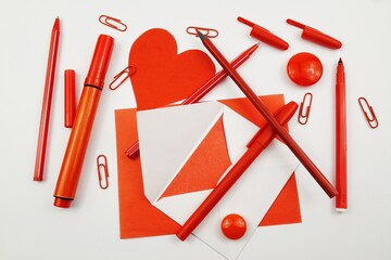 Various stationery in red are laid out on a white table