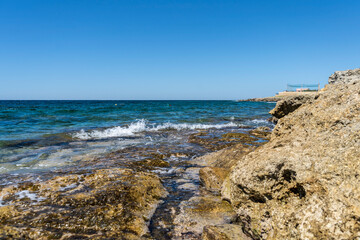 Fototapeta na wymiar Rocky shore of Posto Rosso, Salento, Puglia, Southern Italy, in a sunny summer day, with bright colors, clear water and blue sky. 