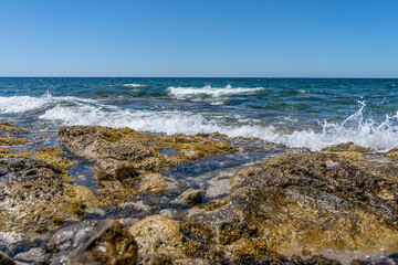 Rocky shore of Posto Rosso, Salento, Puglia, Southern Italy, in a sunny summer day, with bright colors, clear water and blue sky. 