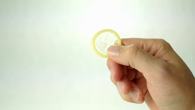 Male hand holding a condom, concept of safe sex. Isolated on white background.