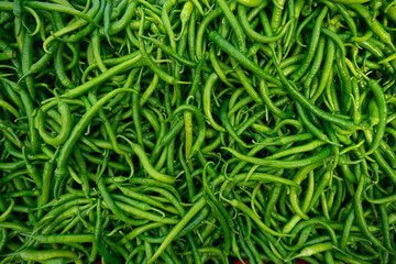 Fresh green chili peppers in the basket for sale on street market. a large amount of hot chili pepper pattern for the background.