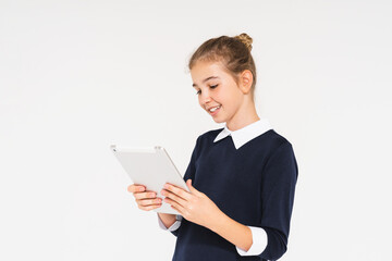 Cute smiling teen girl in school uniform with tablet in her hands isolated on white background