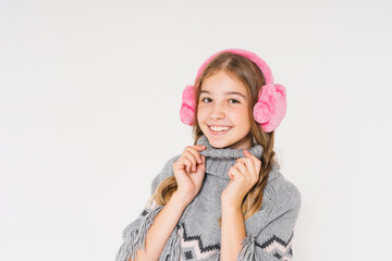 Cute smiling teenage girl in pink fur headphones and gray poncho looks up isolated on the white background