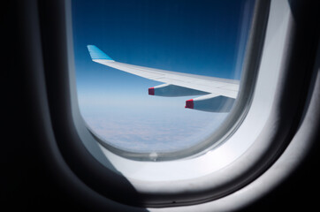 Fototapeta premium Airplane wing view through windows from place interior. Plane wing against clear blue sky during flight. 