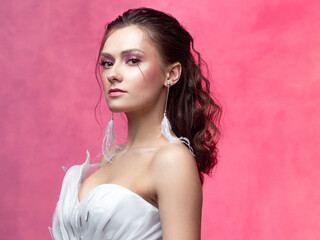 Portrait of a young beautiful woman in elegant white, textured pink background.