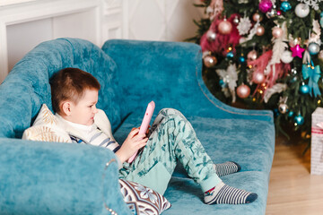 Baby plays in tablet sitting on couch