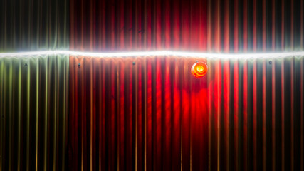 Title: Led strip and flasher warning light on corrugated aluminum fence of a building site

