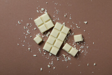 Tasty white chocolate on brown background, flat lay