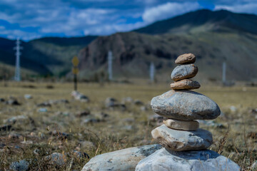 Stacked balanced colorful rocks large and small against the backdrop of mountains
