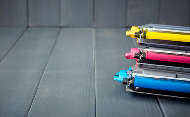 Three yellow, cyan and magenta toner cartridges for replacement in a color printer on wooden...