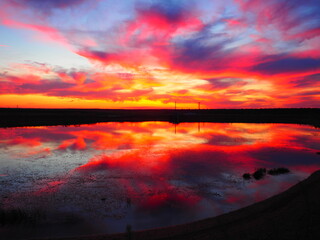 Fototapeta na wymiar Red and orange sky reflected in a lake at sunset