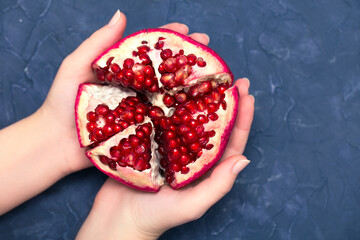 Fresh and ripe pomegranate fruit in women's palms, close up