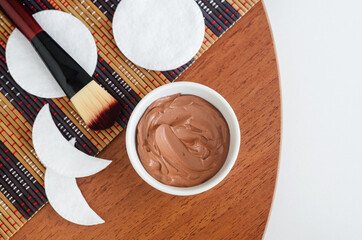 Red bentonite clay in the small white bowl, handmade eye patches, cotton pads and make-up brush. Diy facial or hair mask, body wrap recipe. Natural beauty treatment and spa. Top view, copy space.