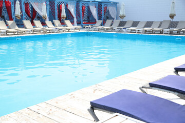 Outdoor swimming pool with sunbeds at resort on sunny day