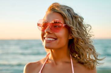 Attractive Caucasian woman in bikini swimsuit strolls on the beach at sunrise enjoying the sound of the waves.