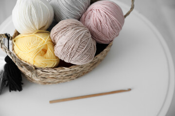 Fototapeta na wymiar Clews in wicker basket and crochet on table indoors, above view. Engaging in hobby