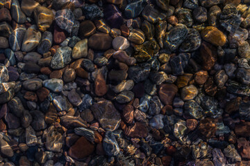 bright colored blue gold small pebbles in clear water sparkles in light of the sun, lake baikal