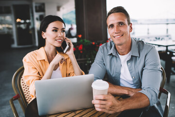 Cheerful diverse man and woman sitting in cafe with gadgets