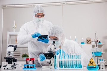 Two Scientists in PPE Suit working in Lab while Checking Result of Blood Sample testing. Blue Tone....