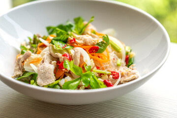 Thai food, spicy salad of cleared noodles or Yum Woon Sen in Thailand language. Close up food in white bowl on table, natural light. © dul_ny