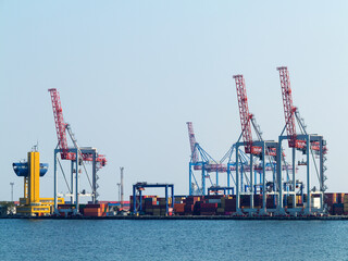 Fototapeta premium Large cranes for loading goods on large marine cargo ships at the container terminal in the port of Odessa sea port on a foggy day
