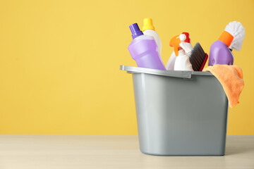 Bucket with cleaning products and tools on grey table. Space for text