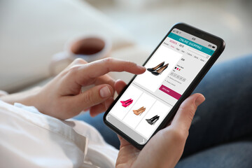 Woman shopping online via smartphone indoors, closeup